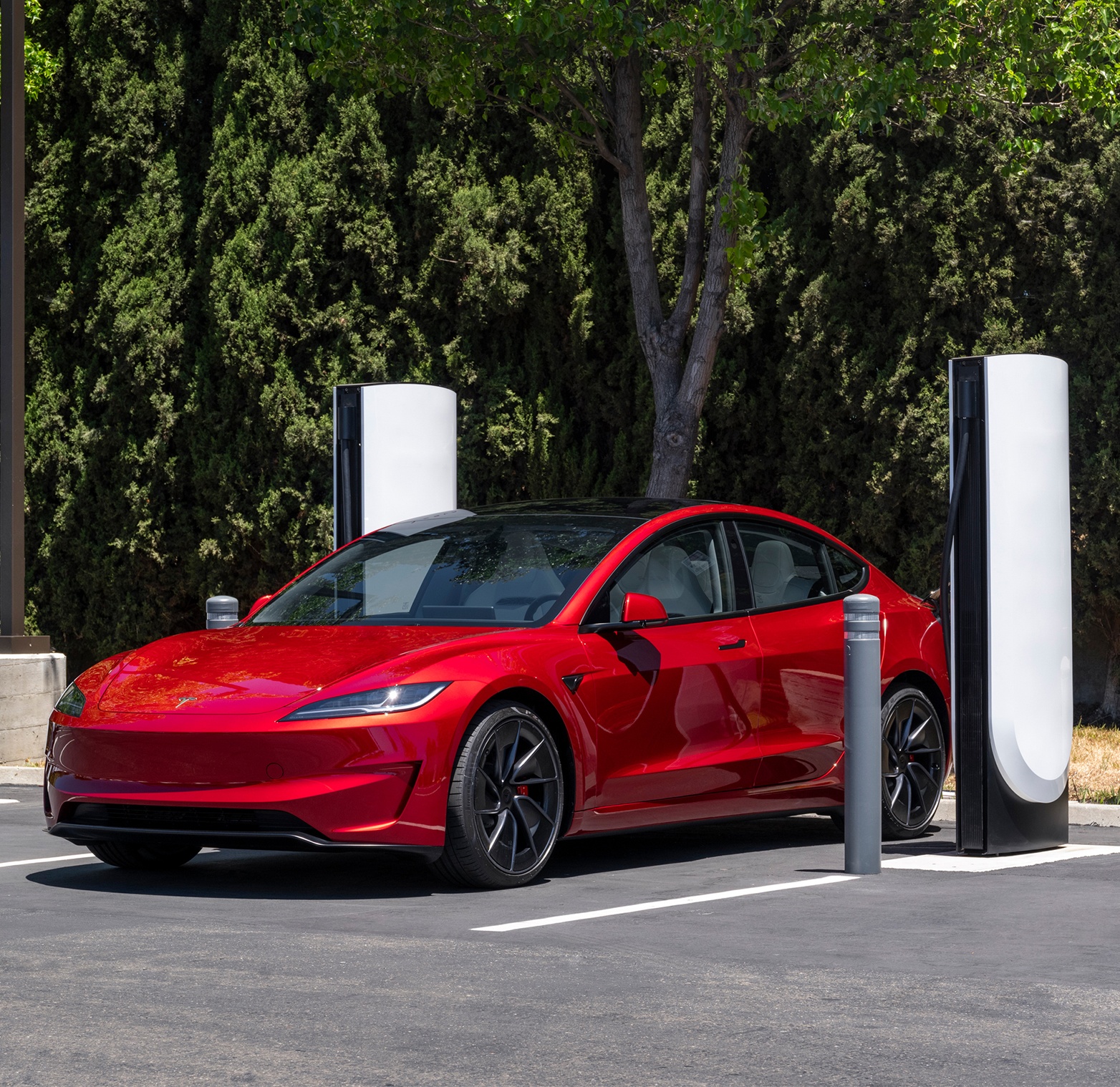 Red Tesla Model 3 recharging at Tesla Supercharger station