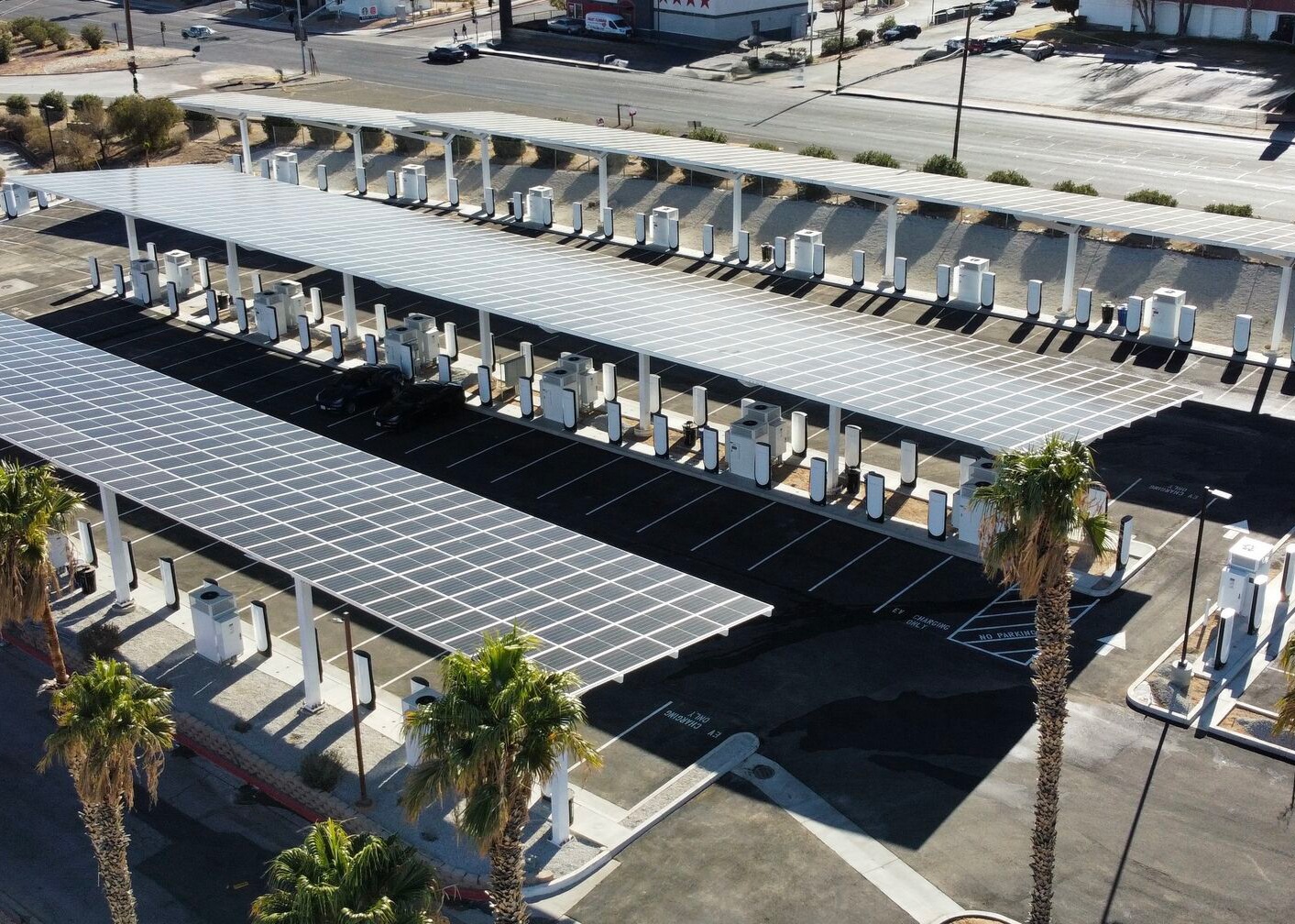 Tesla Supercharger station with large number of available spaces, all shaded by solar-panel-topped coverings.