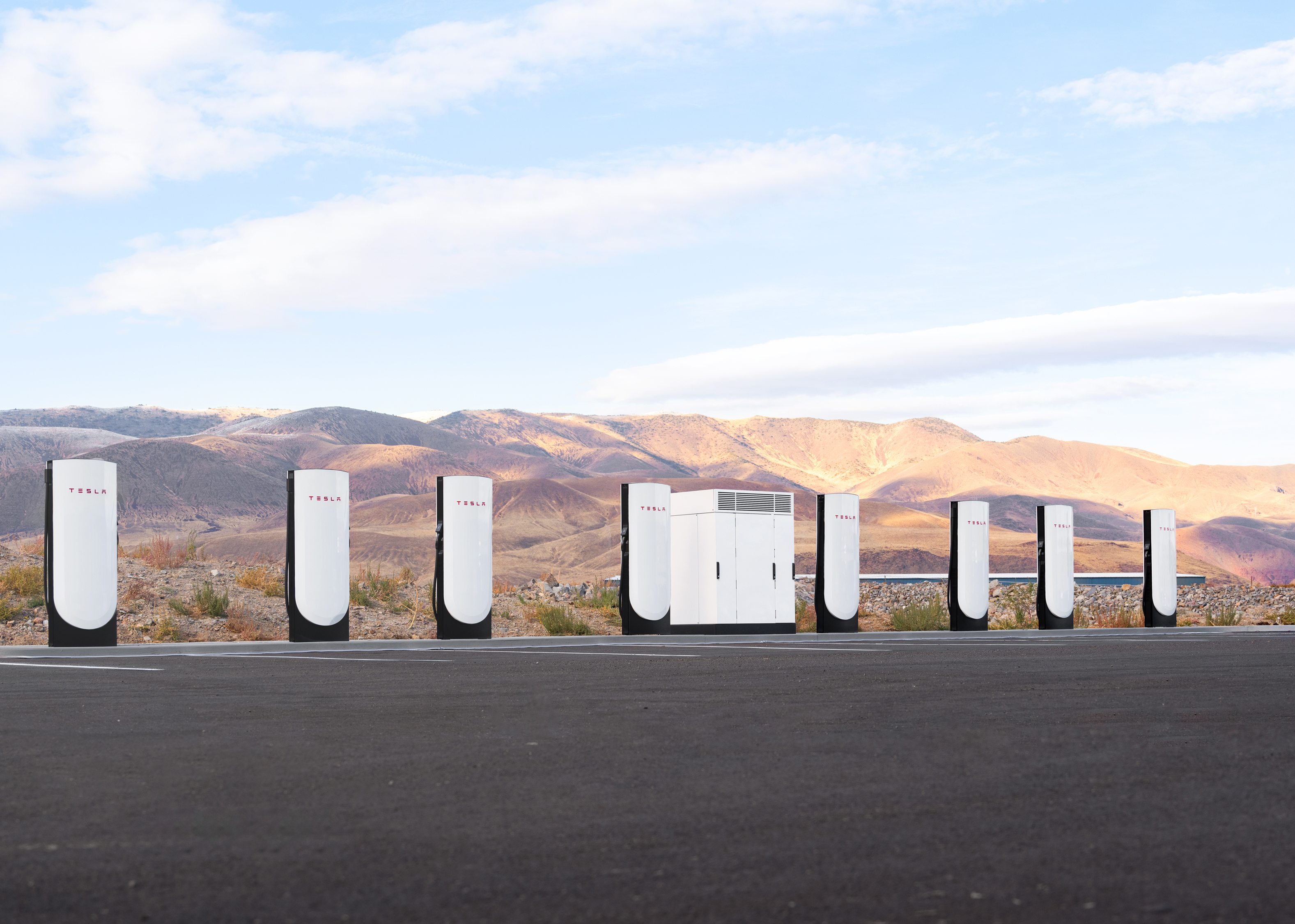 Row of 8 Tesla Superchargers set in front of a scenic desert background